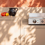 Cozinha exterior Pilotis branco creme com plancha Vivaplancha e bancada em cerâmica branca.
::visuel:creme