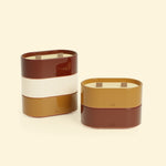 Bougies Totem S Rouge oxyde – Citronnelle & Géranium et Brun terre de sienne – Citronnelle & Fleur d’oranger, deux bougies ovales à double mèche en bois, posées sur un fond beige clair 