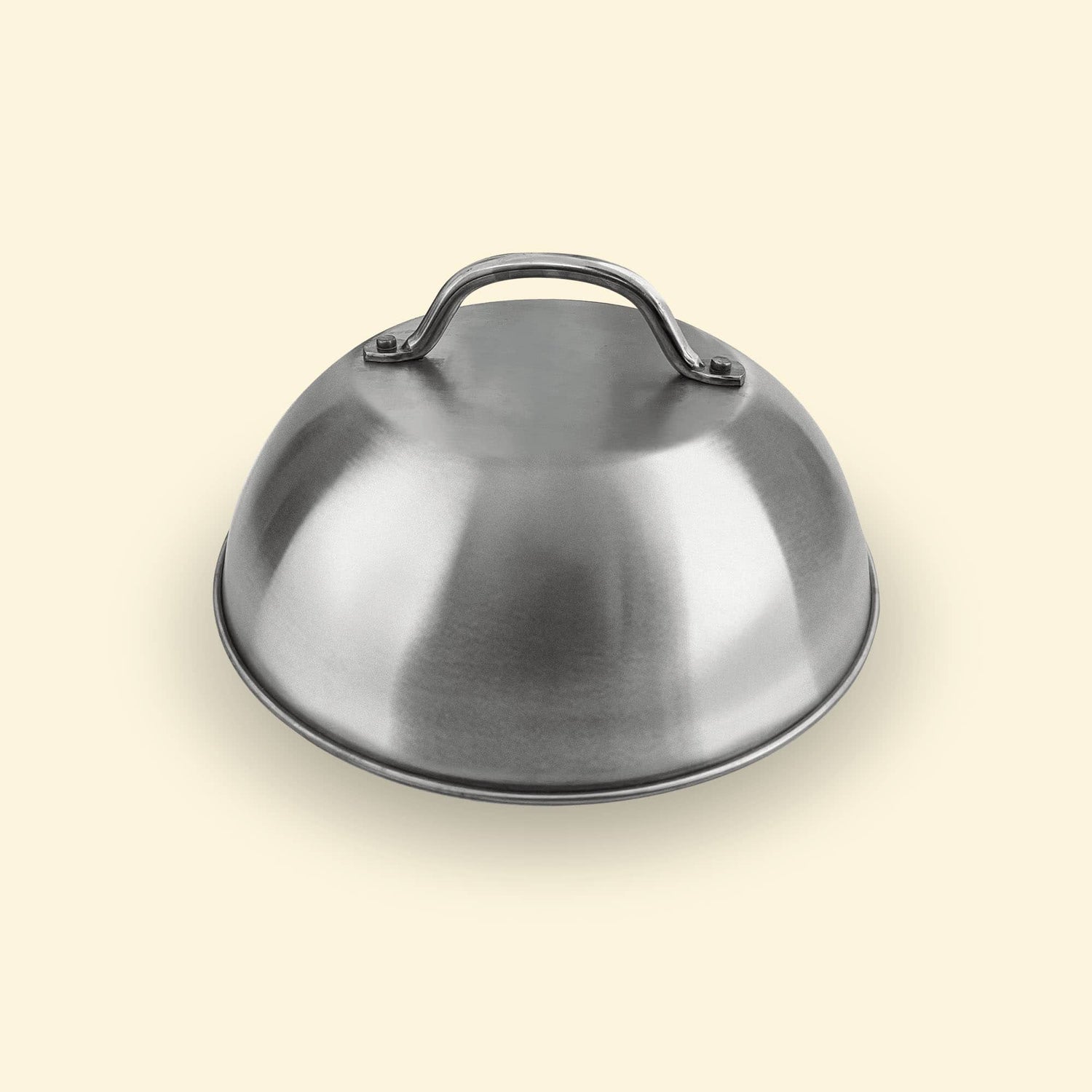 Cloche de cuisson en inox posée sur fond uni, accessoire pour plancha permettant de créer un effet four et de maintenir la chaleur.