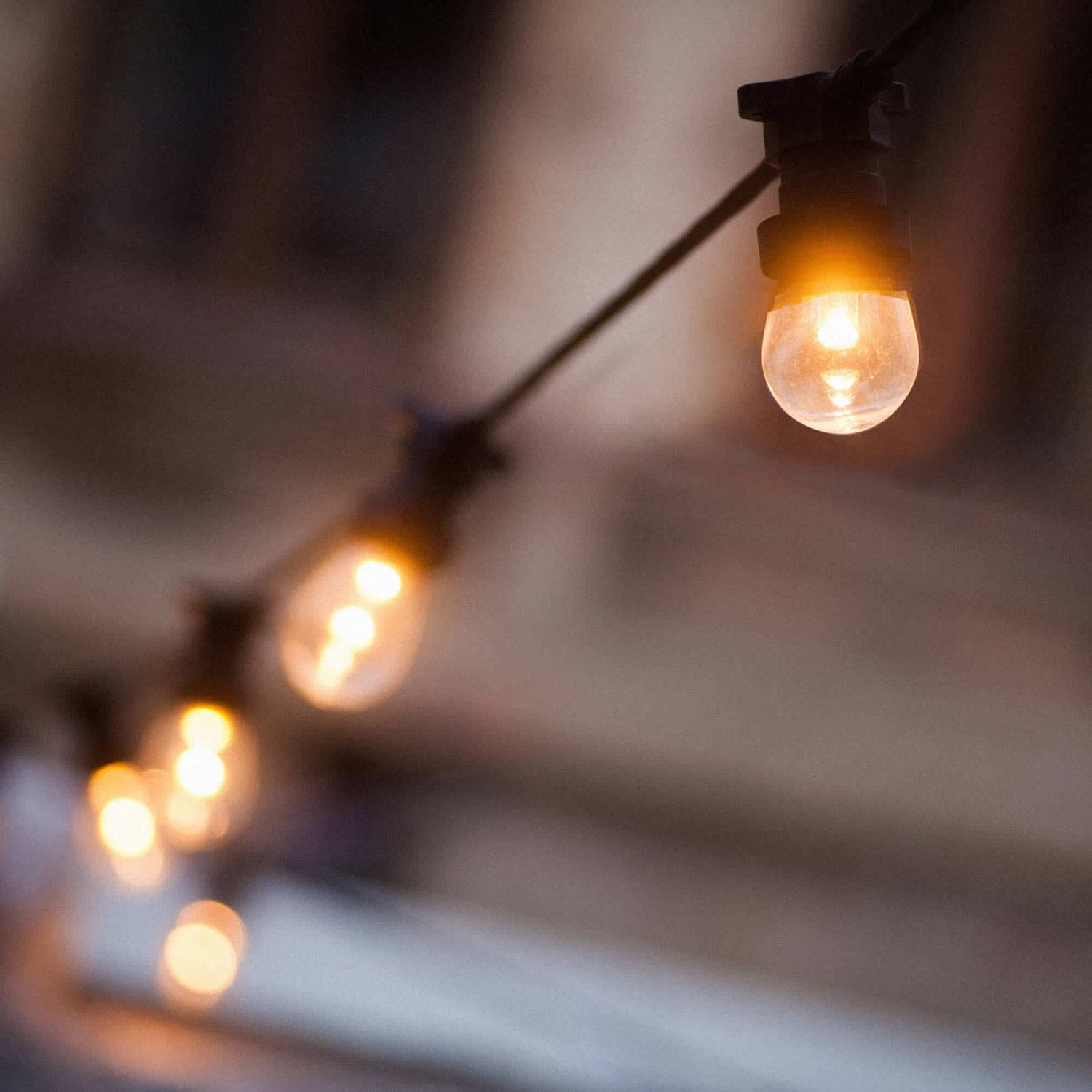 Guirlande lumineuse d’extérieur avec ampoules rondes transparentes diffusant une lumière chaude, suspendue sur un câble noir pour une ambiance conviviale et élégante en soirée.