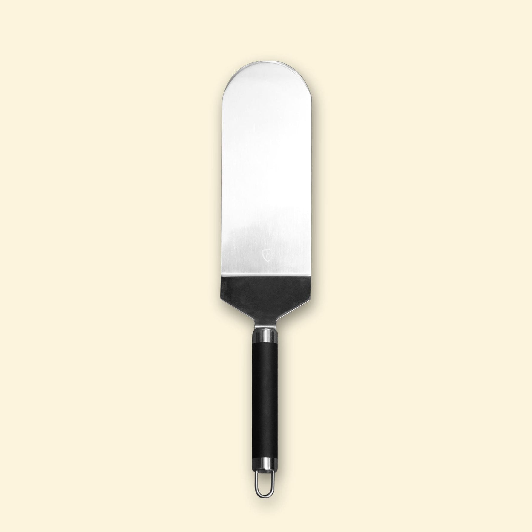 Grande spatule à poisson en inox avec manche noir, présentée sur fond beige.